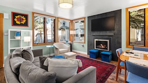 Ein modernes Wohnzimmer mit einem grauen Sofa, einem weißen Sessel, einem roten Teppich und einem Kamin.