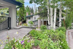 A residential area with a gated entrance, a covered porch, and a landscaped garden with various plants and flowers. - Snowmass Townhome Near Base Village! Pool/HT, W/D, Gas FP & Parking (Snowmass Village)