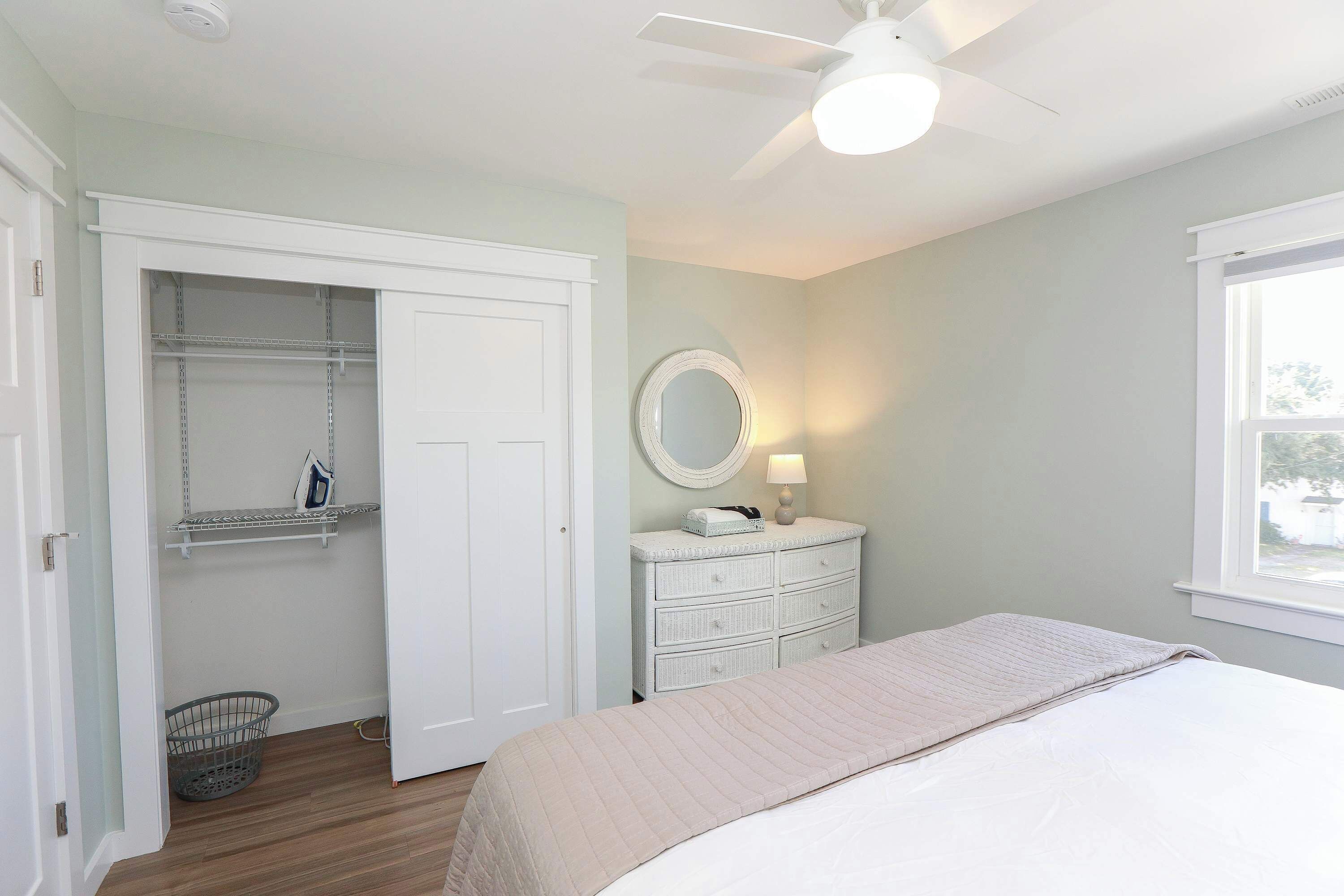 Une chambre à coucher avec un lit, une commode, un miroir et un placard.