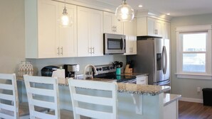A modern kitchen with white cabinets, stainless steel appliances, and a granite countertop. - Sojourn's Sea Views with Balcony Sleeps 4 (Virginia Beach)