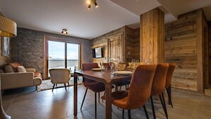 Un comedor moderno con una mesa y sillas de madera, una pared de piedra y un amplio ventanal con vistas al agua.