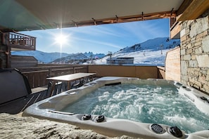 A hot tub with a view of a snowy mountain landscape.