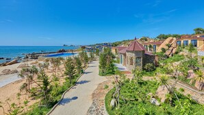 Une station balnéaire dotée d’une promenade dallée, d’une piscine et d’une vue sur la mer.