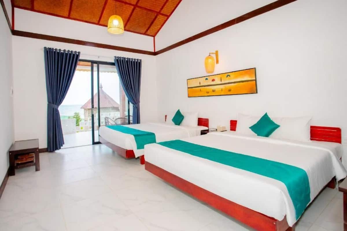 Habitación de hotel con dos camas, un balcón y un cuadro en la pared.