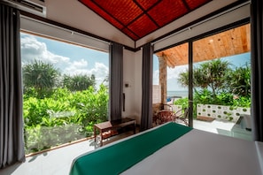 Ein Schlafzimmer mit einem großen Bett, einem kleinen Tisch und Blick auf den Ozean.