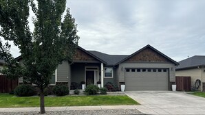 A modern two-story house with a garage, a covered porch, and a well-maintained lawn.