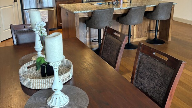 A modern kitchen with wooden cabinets, a stainless steel refrigerator, and a large island with bar stools.