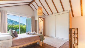 A bedroom with a bed, a large window, and a view of greenery.