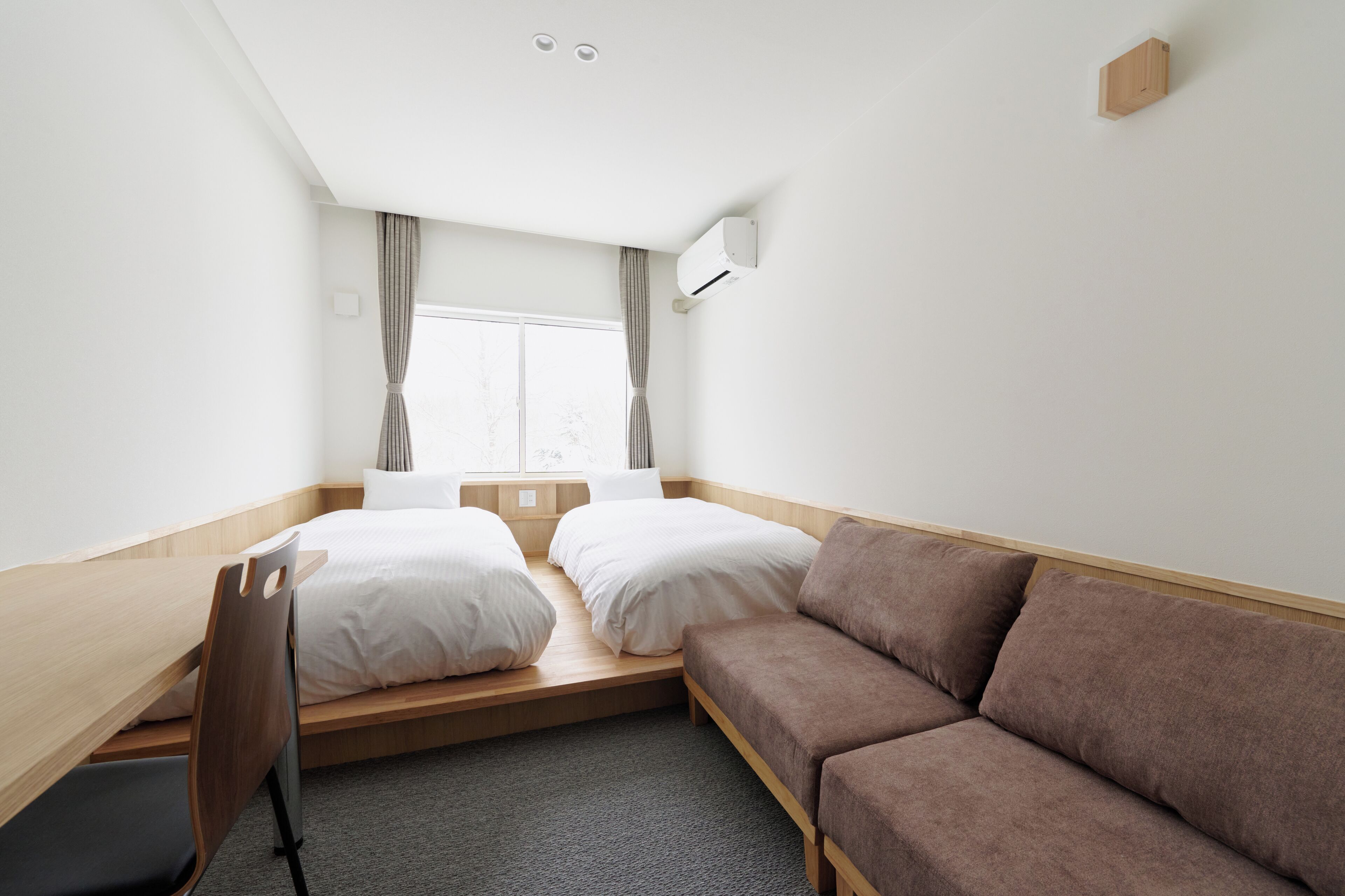 Une chambre d’hôtel de taille réduite, comprenant un lit, un canapé, un bureau et une chaise.