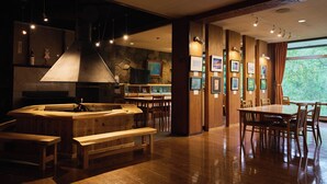 A restaurant with a wooden bar, seating area, and framed pictures on the walls. - Ishinoyu Lodge (Yamanouchi)