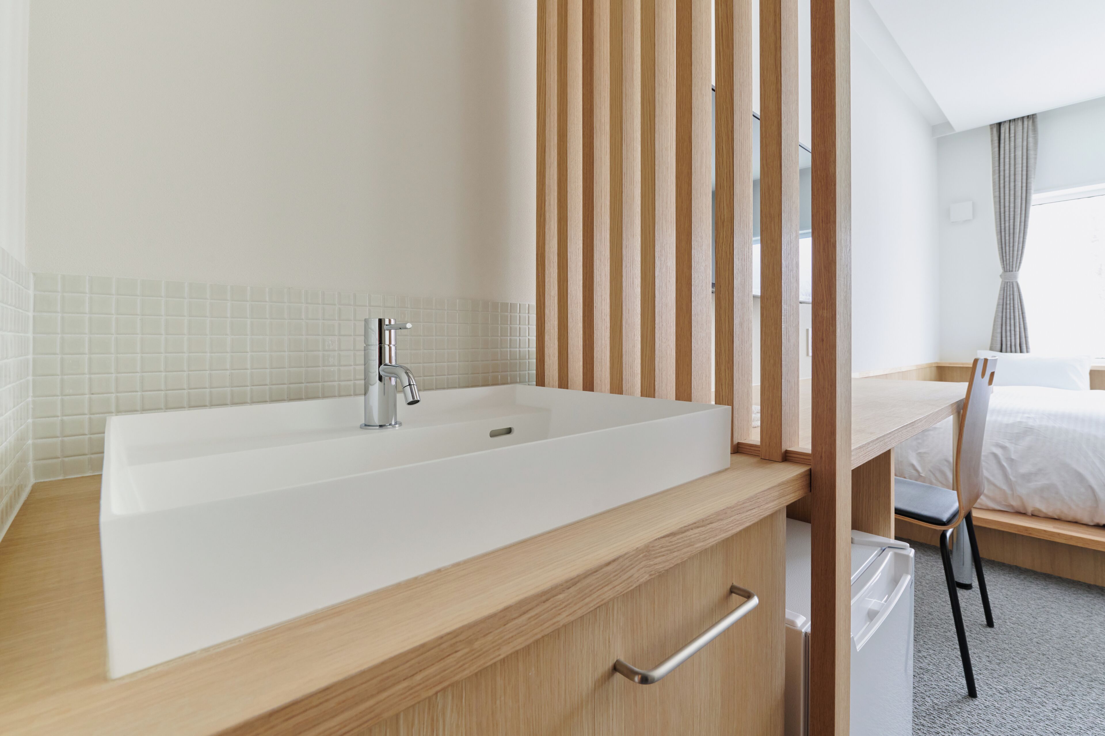 Un baño moderno con una bañera blanca grande, tocador de madera y un escritorio con una silla.