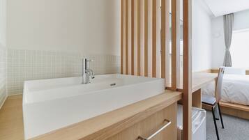 A modern bathroom with a large white bathtub, wooden vanity, and a desk with a chair.