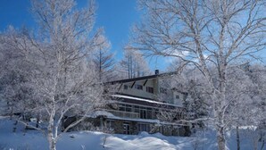 A two-story house surrounded by snow-covered trees. - Ishinoyu Lodge (Yamanouchi)