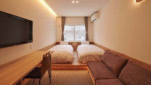 A hotel room with a bed, a desk, a chair, a TV, and a window with curtains. - Ishinoyu Lodge (Yamanouchi)