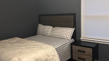 Une chambre à coucher avec un lit, une table de chevet et une fenêtre avec des stores.