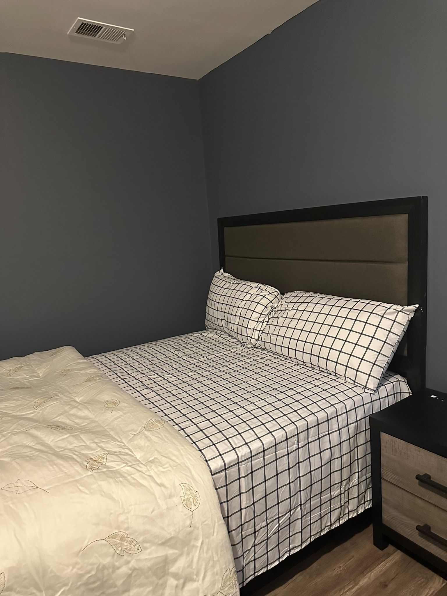 A bedroom with a bed, a nightstand, and a drawer unit.