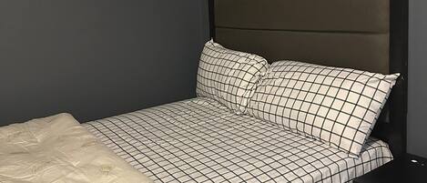 A bedroom with a bed, a nightstand, and a drawer unit.