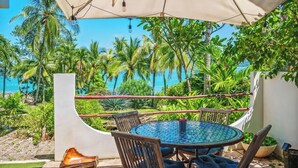 A round table with chairs and a hammock under a canopy, overlooking a beach with palm trees and the ocean. - Beachfront paradise in Flamingo Marina - FM407 (Flamingo)