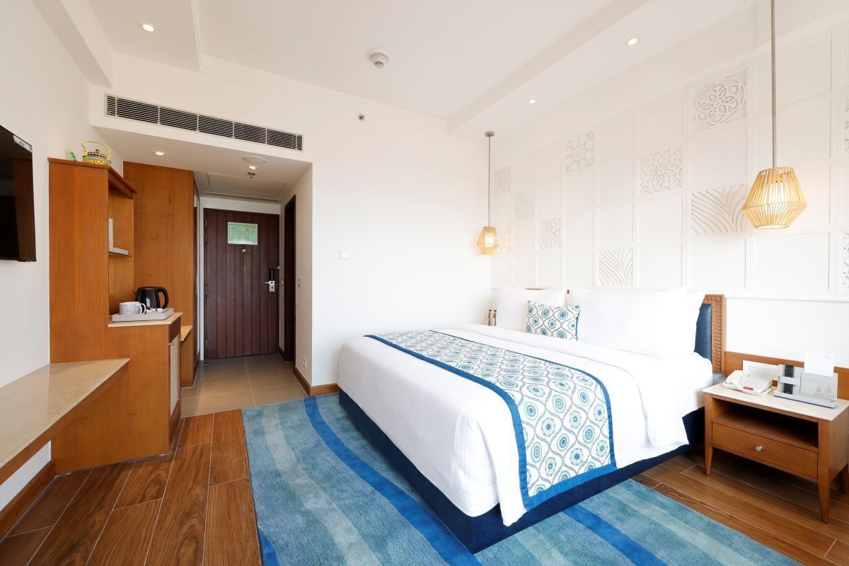 Una habitación de hotel con cama, mesita de noche y televisión.