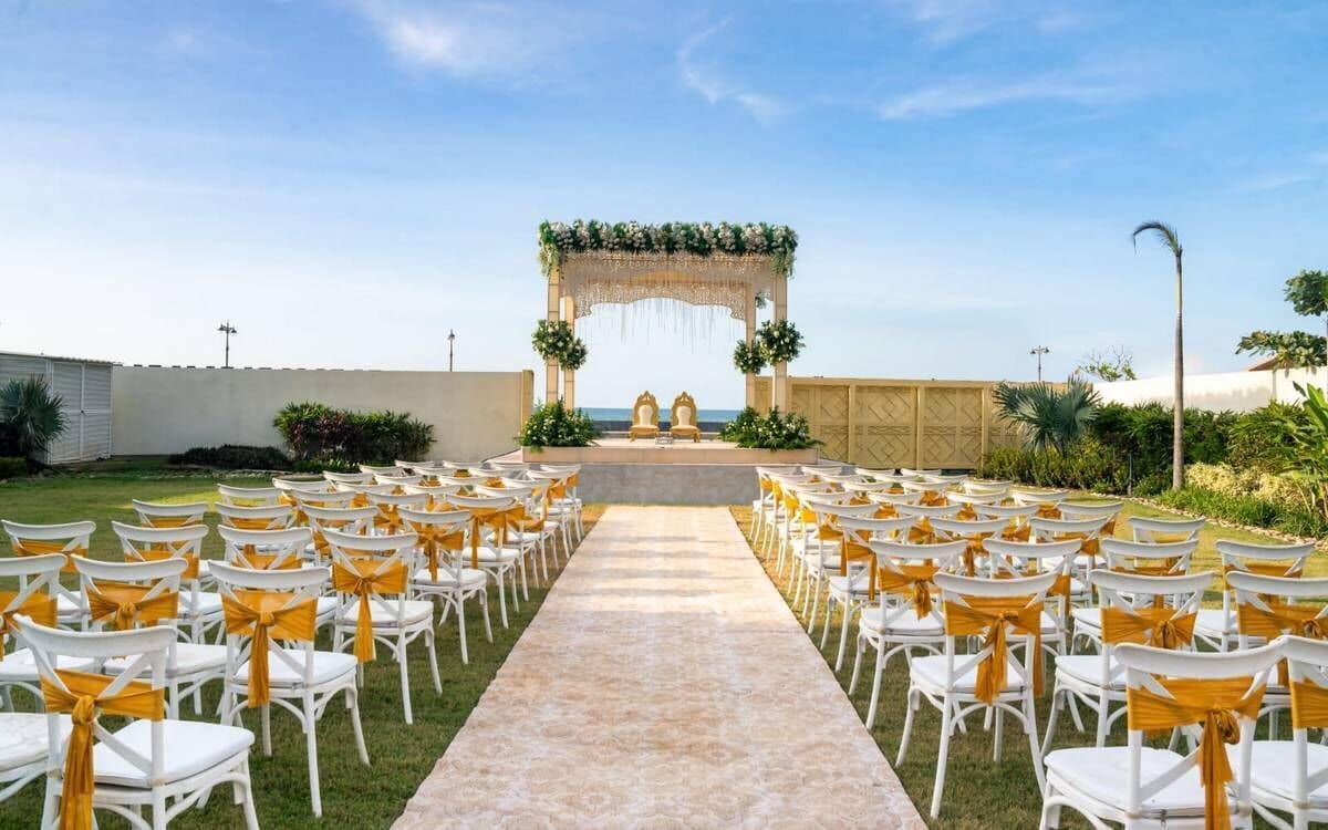 Un pasillo nupcial con sillas blancas y un arco floral.