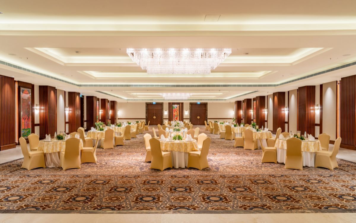 A banquet hall with round tables, chairs, and a chandelier.