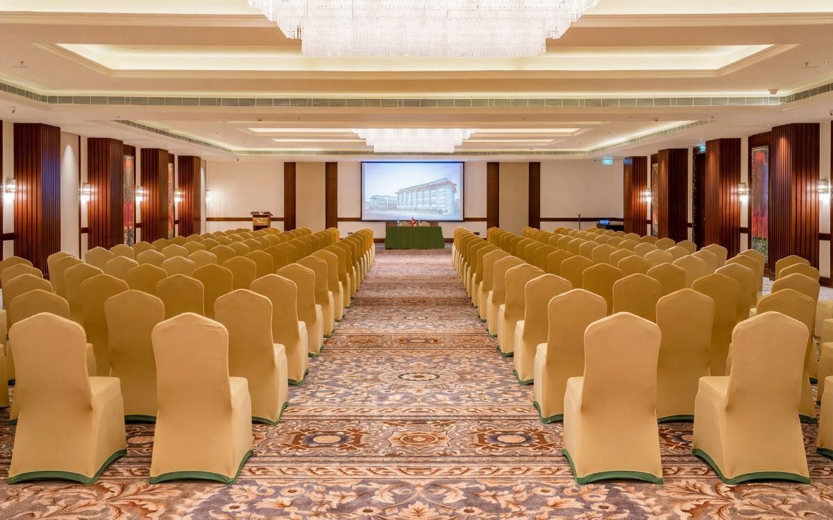 A conference room with rows of chairs, a carpeted floor, and a large screen at the front.