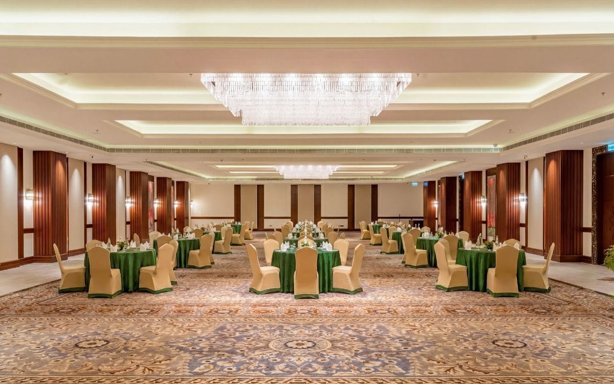 A banquet hall with round tables, chairs, and a chandelier.
