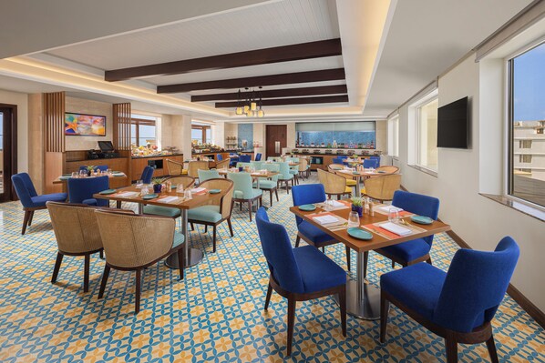 Un amplio vestíbulo de hotel con varias zonas de comedor, un bar y vistas a la ciudad.