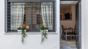 Une fenêtre avec des barreaux en métal, une petite table avec des chaises et un téléviseur fixé au mur.