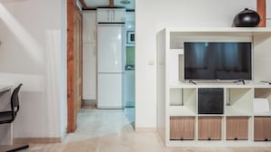 Eine moderne Küche mit Einbaukühlschrank und Mikrowelle, ein weißer TV-Schrank mit Flachbildfernseher und eine Holzbalkendecke.