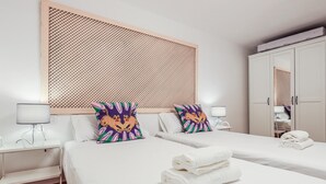 Ein Hotelzimmer mit zwei Betten, einem großen gewobenen Kopfteil, weißer Bettwäsche und dekorativen Kissen.