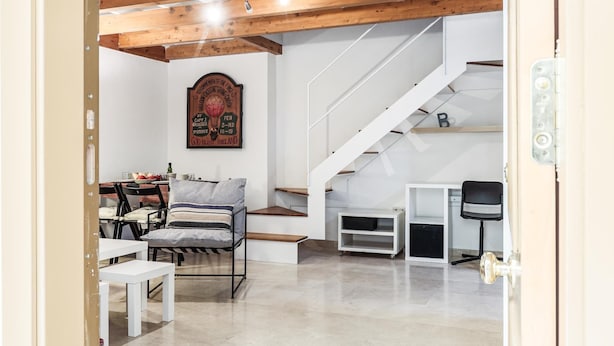 Ein modernes Interieur mit Holzbalkendecke, einer Treppe, einem Bett, einem Schreibtisch und einem Wandbild.