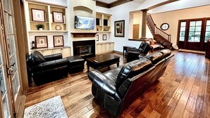 A spacious living room with a fireplace, leather sofas, a television, and a staircase leading to another level. -  Beautiful 4BR/4BA.Close to HHI/SAV/BEU, 5 minutes to Palmetto Bluff's entrance  (Bluffton)
