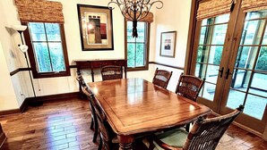A dining room with a large wooden table, six chairs, a chandelier, and large windows with blinds. -  Beautiful 4BR/4BA.Close to HHI/SAV/BEU, 5 minutes to Palmetto Bluff's entrance  (Bluffton)