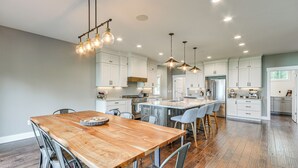 Una cocina amplia con una mesa de comedor de madera, iluminación moderna y muebles de cocina blancos.