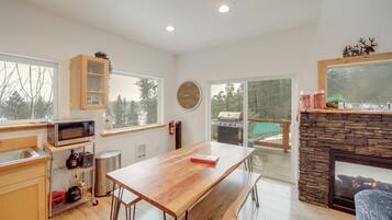 A modern kitchen with a wooden table, a microwave, and a stone fireplace.