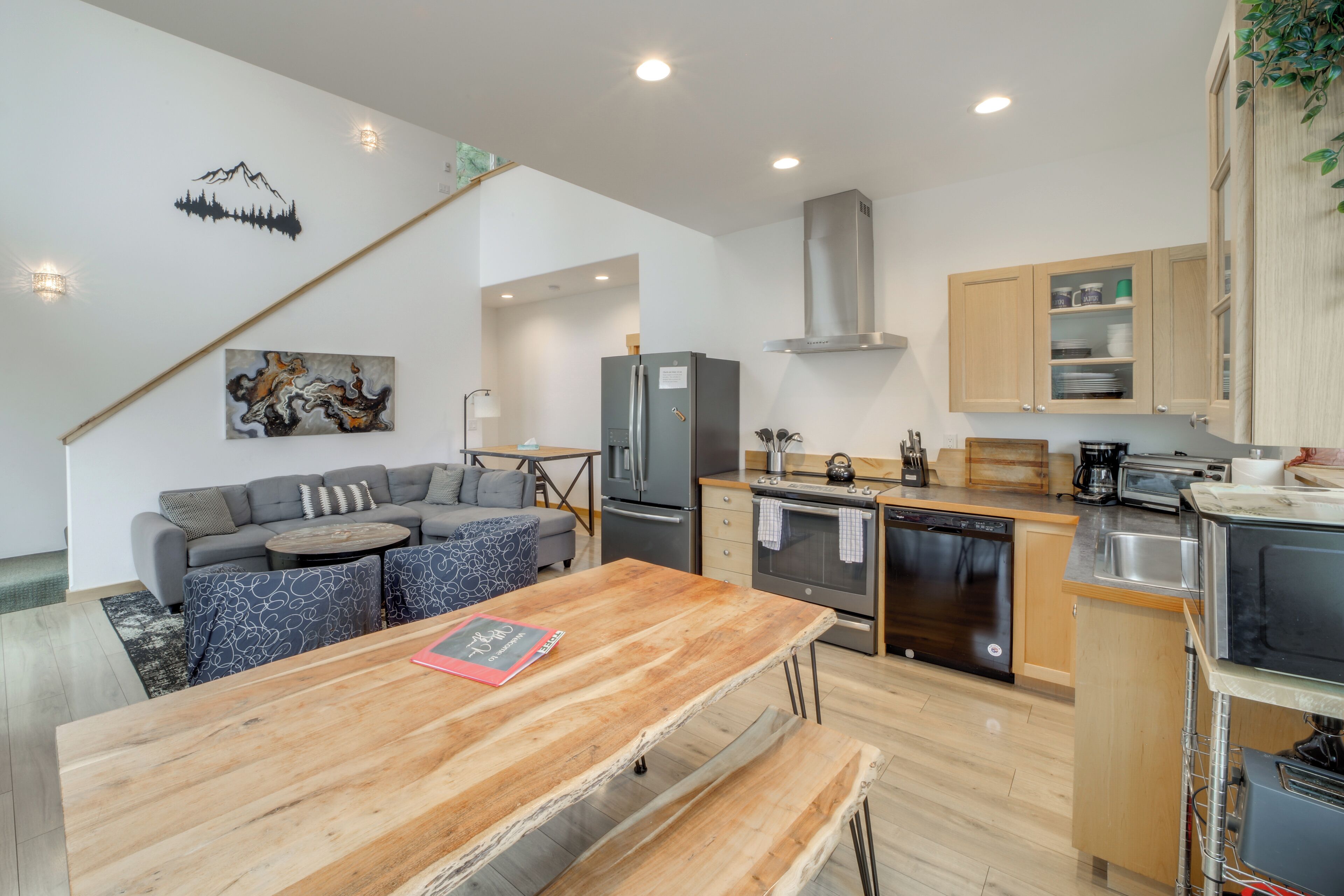 Eine moderne Küche mit Holztisch, integrierten Geräten und einer gemütlichen Sitzecke mit Sofa und Sesseln.