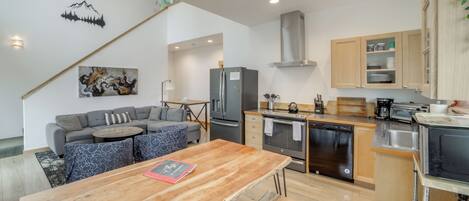 Eine moderne Küche mit Holztisch, integrierten Geräten und einer gemütlichen Sitzecke mit Sofa und Sesseln.