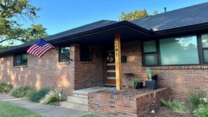 A two-story brick house with a front porch, an American flag, and a mailbox. - Mid-West Mod-1 mile to OU-Central Norman-Sleeps 16 (Norman)
