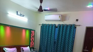 Habitación de hotel con cama, escritorio, silla, aire acondicionado y cortinas.