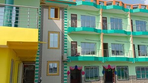 Un edificio de varios pisos con balcones y una sección amarilla a la izquierda.