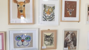 A wall of framed animal paintings, including a deer, tiger, cat, and dog.