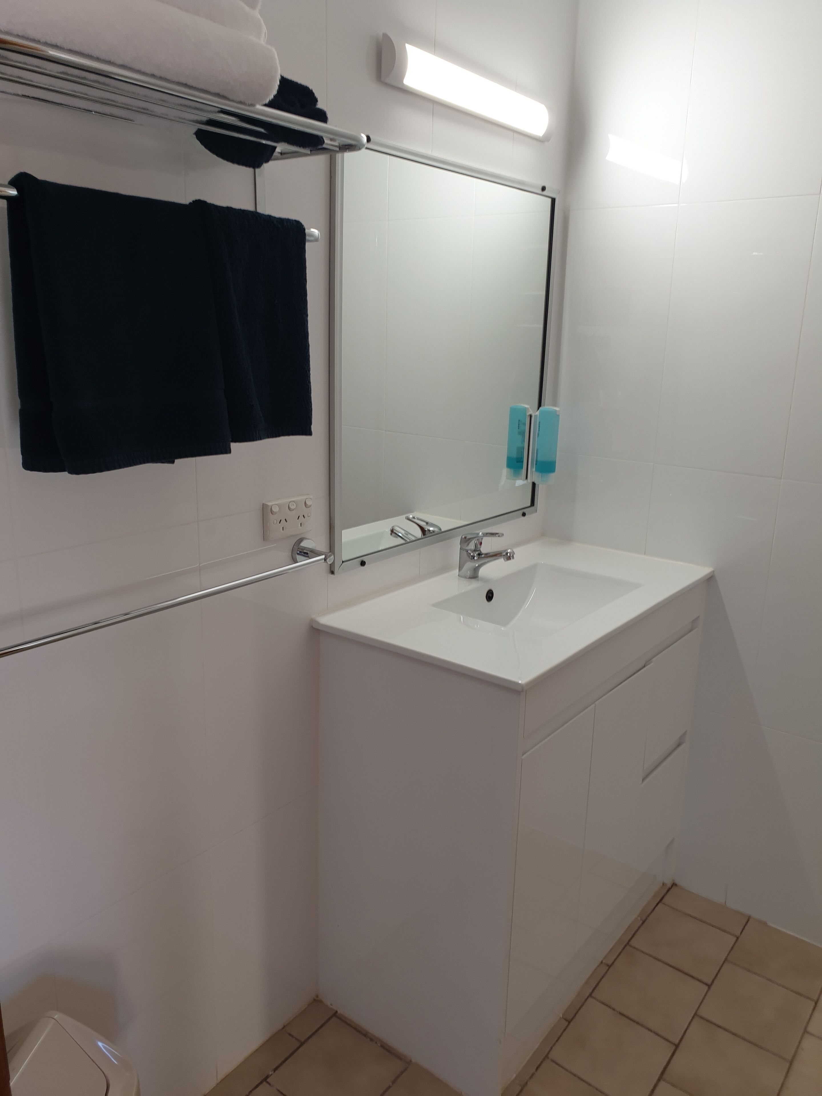 A bathroom with a white sink, a mirror, a towel rack, and a hand dryer.