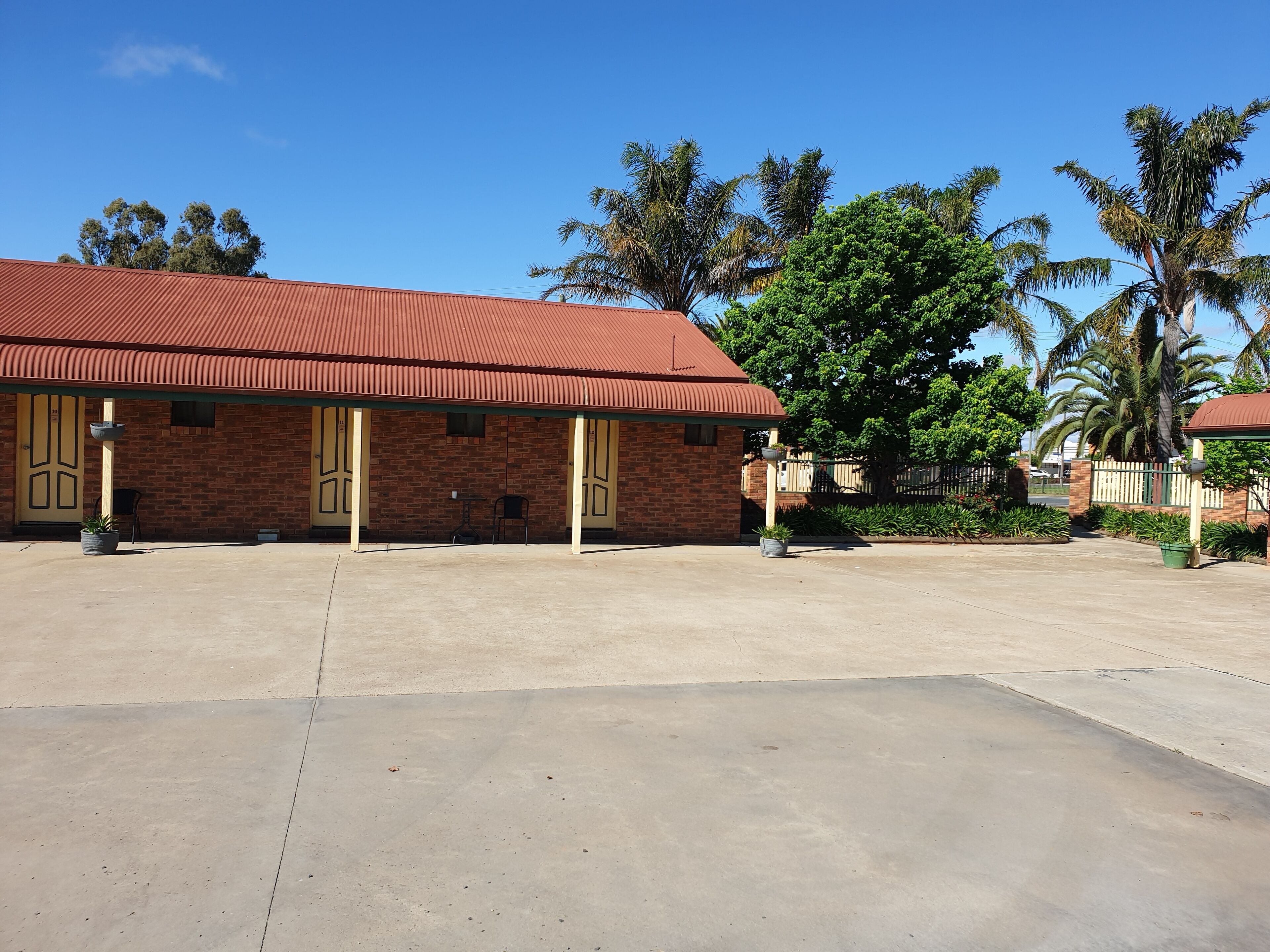A building with a red roof and brick walls, featuring two doors and a small table.