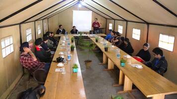 Ein Zelt als Besprechungsraum mit langem Tisch, Stühlen und einer Projektionsleinwand.