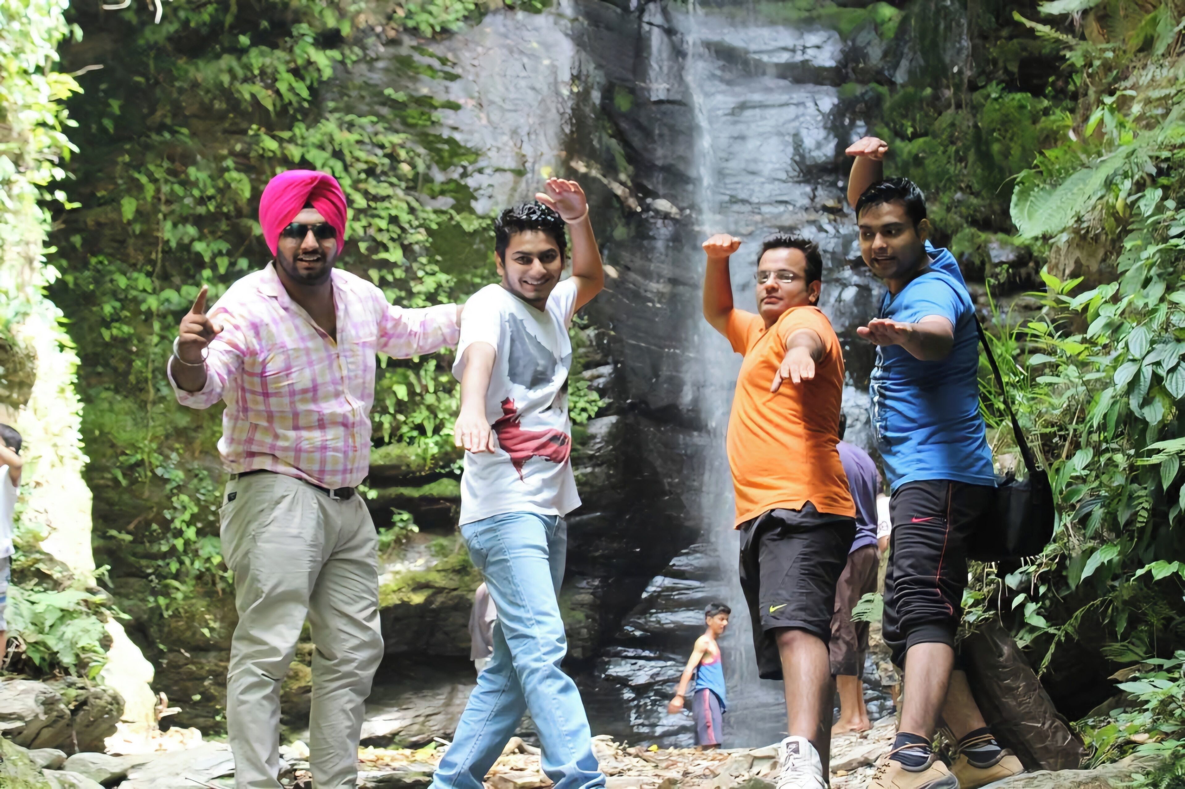 Un grupo de personas en un entorno natural, con una cascada al fondo.