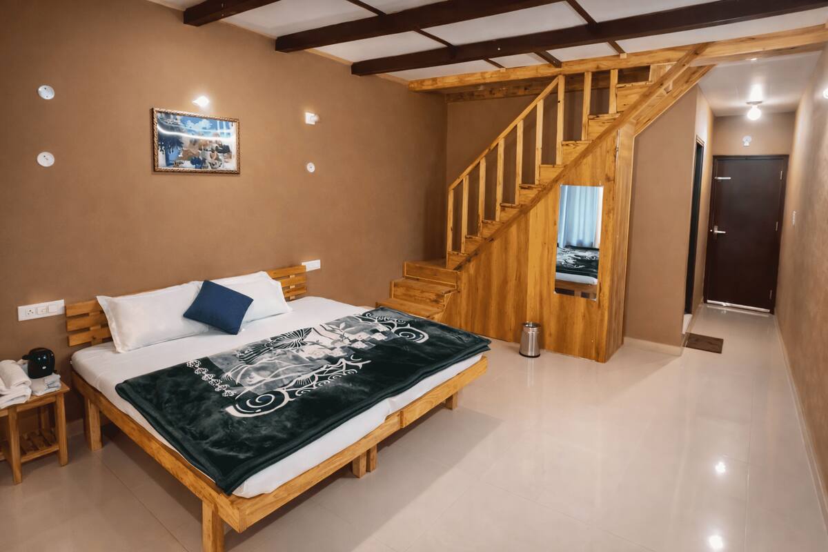 Ein Schlafzimmer mit einem hölzernen Bett, einer Holztreppe, einem kleinen Nachttisch und einem an der Wand hängenden Bild.