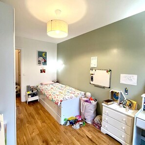 Une chambre à coucher comprenant un lit, une commode et un bureau fixé au mur.