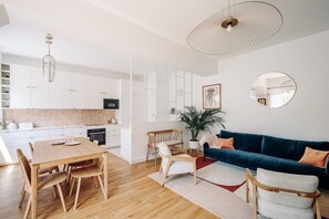 Una sala moderna con una mesa de comedor de madera, un sofá azul y un espejo grande en la pared.