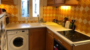 A compact kitchen with a washing machine, a sink, and a stove.